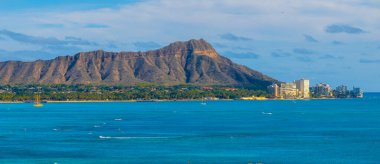 Pasifik Okyanusu, engebeli sırtları, küçük tekneleri, sörfçüleri, Honolulu silueti, kumlu plajları ve yemyeşil yeşillikleri olan Oahu adasındaki Diamond Head Krateri..