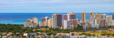 Yüksek binaların, turkuaz suların, yelkenlilerin, yemyeşil suların ve berrak gökyüzünün bulunduğu canlı bir Honolulu, Hawaii manzarası..