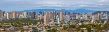 Yüksek binalar, yerleşim alanları, yeşil alanlar ve bulutlu gökyüzünün altındaki Ko olau dağ sırasının yer aldığı Honolulu, Hawaii manzarası.