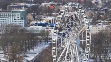 Riga, Letonya 'da karla kaplı kentsel manzaralarla çevrili durgun bir dönme dolap. Kamera tarihi ve modern mimariyi ortaya çıkarıyor..