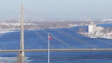 Açık bir kış gününde Riga 'nın havadan görünüşü, Daugava Nehri' ni, bir köprüyü, Letonya Ulusal Kütüphanesini ve vinçli liman alanını gösteriyor..