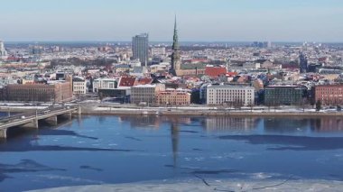 Riga, Letonya 'nın havadan görünüşü, Daugava Nehri' ni buzlu, işlek bir köprü, Eski Şehir simgeleri ve açık mavi bir gökyüzü ile gösteriyor..