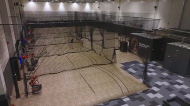 Ağ ile çevrili kapalı kapalı basketbol sahaları, yukarıdan görülüyor. Baller etiketli bir resepsiyon alanında modern dekorasyon ve döşemeler yer almaktadır..