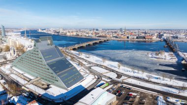Litvanya 'nın Riga kentinin havadan görünüşü, Ulusal Kütüphaneler modern mimarisi, donmuş Daugava Nehri, ve kışın tarihi şehir kuleleri.