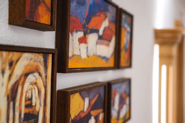 Beyaz bir duvarda kırmızı çatıları olan, ahşap çerçeveli ve sağında ahşap bir mimari detay bulunan canlı, soyut resimlere yakın çekim yapın..