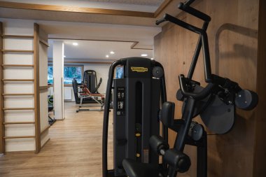 Kapalı spor salonu ekipmanları, ahşap döşeme, tenha ışıklandırma ve Ischgl, Avusturya 'da bulunan ağaç manzaralı bir pencere..