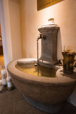 Kavisli bir havzası, pirinçten bir borusu ve zinciri olan şatafatlı taştan bir çeşme. Dekorasyonda Avusturya 'nın Ischgl kentinde mumlar, cam eşyalar ve sıcak ışıklandırma yer alıyor..