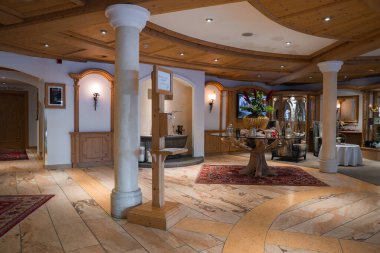 Avusturya 'nın Ischgl kentindeki şık otel lobisinde ahşap tavanlar, mermer döşemeler, çiçek süsü, kırmızı halı ve modern ve geleneksel dekorların karışımı yer alıyor..