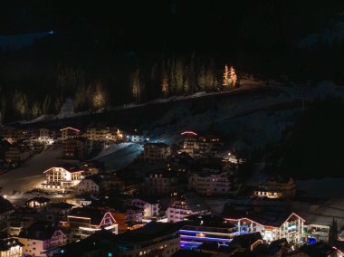 Kar, geceleri sıcak ışıklar, eğimli çatı binaları, şenlikli Noel ağaçları ve ormanlık bir dağ zeminiyle kayak merkezini kapladı..
