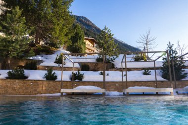 Isıtmalı açık havuz karla kaplı teraslar, ahşap pergolalar ve dinlenme odaları ile çevrili, her zaman yeşil ağaçlara ve dağlara karşı kurulmuş..