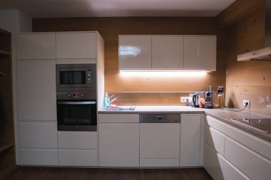 Ischgl, Avusturya 'da lüks bir otelde, beyaz dolaplı, ahşap aksanlı, alet edevatlı ve dolap aydınlatmalı bir mutfak..