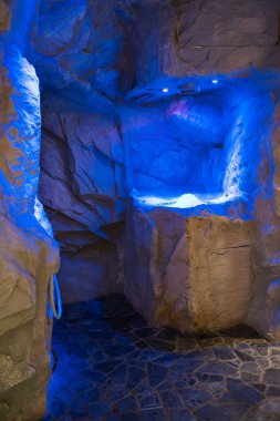 Avusturya 'daki Ischgl kayak merkezinde yer alan, duvarlar gibi dokulu kayalar, koyu taş döşemeler ve mavi ışıklı sakin bir spa merkezi..