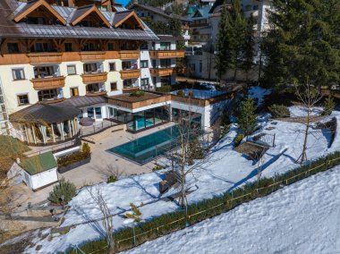 Geleneksel dağ evi tarzı otel ahşap balkonları, eğimli çatısı, ısıtmalı havuzu, terası, karla kaplı zemini ve dağ tatil köyü zeminiyle..