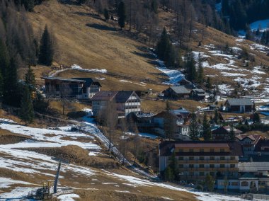 Çok katlı lüks bir otel, karlı tepeler ve seyrek ağaçlarla çevrili geleneksel ahşap ve taş binaları olan küçük bir dağ köyünde duruyor..