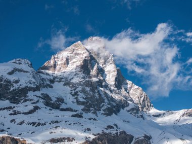 Alplerdeki ikonik Matterhorn Dağı 'nda bir piramit bulunur. Tepe, engebeli kaya oluşumları ve açık mavi gökyüzünün altında kar kaplı yamaçlar..