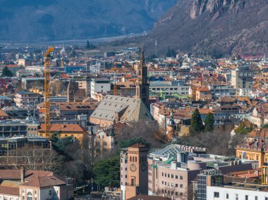 Bolzano, İtalya 'nın havadan görünüşü, Gotik Bolzano Katedrali, renkli binalar, bir saat kulesi ve arka planda ormanlı dağlar..