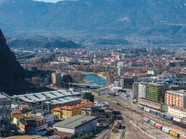 İtalya 'nın Bolzano kentinin havadan görünüşü, arka planda bir demiryolu, bir nehir, modern ve geleneksel mimari ve Dolomite dağları yer almaktadır..