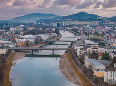 Salzburg, Avusturya 'nın hava perspektifi, Salzach Nehri, birden fazla köprü, tarihi ve modern mimari, tepeler ve uzak dağların yer aldığı.