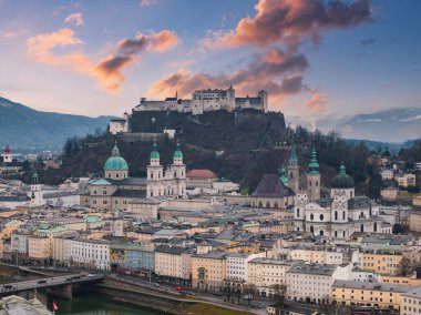 Hohensalzburg Kalesi, barok mimarisi, Salzach Nehri ve canlı turuncu ve pembe gökyüzünün yer aldığı Salzburg, Avusturya 'nın hava manzarası..
