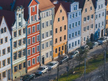 Polonya 'nın Wroclaw şehrinde bir dizi canlı ev dik çatıları, dekoratif gablonları ve ön planda park etmiş arabaları olan ağaç kaplı caddeleri var..