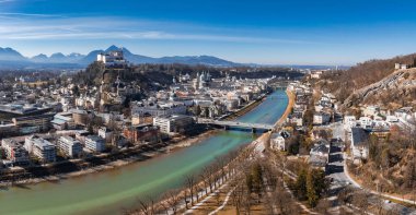 Salzburg, Avusturya 'nın hava manzarası, Salzach Nehri, Hohensalzburg Kalesi, tarihi mimari ve açık mavi gökyüzü altındaki Alpler.