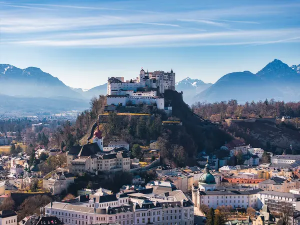 Avusturya 'nın Salzburg kentinin havadan görünüşü, bir tepedeki Hohensalzburg Kalesi, tarihi binalar, kiliseler ve açık gökyüzü altındaki kar kaplı Alpler..