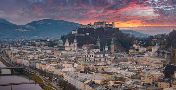 Salzburg, Avusturya 'nın hava manzarası, Hohensalzburg Kalesi, Salzburg Katedrali, Salzach Nehri ve şehrin üzerinde canlı bir günbatımı gökyüzü..