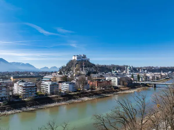 Hohensalzburg Kalesi, Salzburg Nehri, Salzburg Katedrali ve açık bir gökyüzünün altındaki kar örtülü dağların yer aldığı Salzburg, Avusturya 'nın hava manzarası..