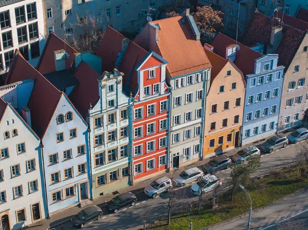 Polonya 'nın Wroclaw şehrinde bir dizi canlı kasaba evi, arka planında sokak ve modern binalar bulunan süslü cepheler ve dik çatılar yer alıyor..