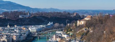 Salzburg, Avusturya 'nın havadan görünüşü, Salzach Nehri, Hohensalzburg Kalesi, Kollegienkirche, yuvarlanan tepeler ve uzak dağlar.