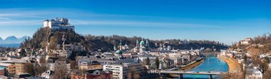 Hohensalzburg Kalesi, Salzach Nehri, tarihi binalar ve açık mavi gökyüzünün altındaki kar kaplı dağların yer aldığı Salzburg, Avusturya 'nın hava manzarası..