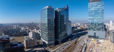 Yansıtıcı ve eğimli kuleler de dahil olmak üzere, daha küçük binalar ve inşaatlarla çevrili, modern Warsaw 'ların hava manzarası..
