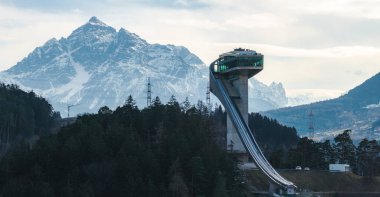Avusturya 'nın Innsbruck kentindeki Bergisel Kayak Atlayışı' nda modern mimari, yoğun ormanlar ve arka planda kar tepeleri yer almaktadır..