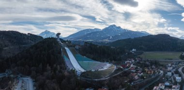 Avusturya 'nın Innsbruck kentindeki Bergisel Kayak Atlayışı' nın hava manzarasında kulesi, orman tepeleri, yerleşim alanları ve kar kaplı Tyrolean Alpleri yer alıyor..