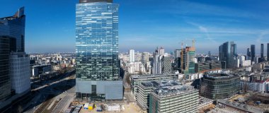 Polonya 'nın Varşova şehrinde cam gökdelenler, inşaat vinçleri, ofis binaları, yollar ve açık gökyüzü altında kentsel altyapı.