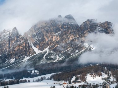 İtalya, Cortina dAmpezzo 'nun hava manzarası, karla kaplı yamaçlar, engebeli Dolomitler tepeler, sis ve vadideki görülebilir şehir binaları..