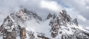 İtalya 'nın Cortina yakınlarındaki Dolomite tepelerini kar kapladı, kısmen sisle kaplıydı. İnce ağaçlar alçak yamaçlarda, engebeli araziyle çelişiyor..
