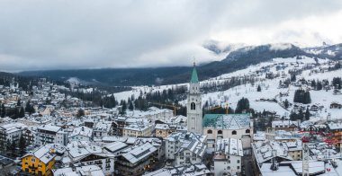 İtalya 'nın Cortina dAmpezzo kentinin havadan görünüşü, Basilica Minore dei Santi Filippo ve Giacomo' nun yer aldığı, karla kaplı çatıları ve etrafındaki kayak yamaçlarını gösteriyor..