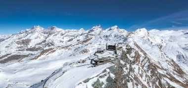 Alpleri kaplayan Alpleri arka planda Matterhorn, bir sırtta Gornergrat Gözlemevi, kayak yamaçları ve İsviçre 'nin Zermatt şehrinde açık mavi bir gökyüzü kapladı..