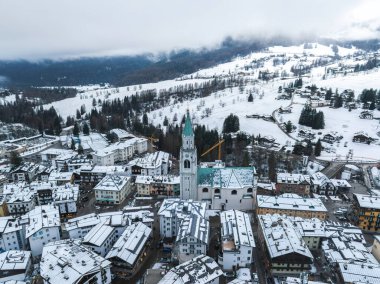 İtalya 'nın Dolomites kentindeki Cortina ve Ampezzo' nun hava manzarasında, bazilika Minore çan kulesi, karla kaplı çatılar ve inşaat vinçleri yer alıyor..