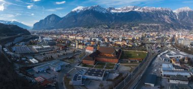 Avusturya 'nın Innsbruck kentinin havadan görünüşü, tarihi ve modern mimarinin bir karışımı, bir demiryolu hattı ve arka planda kar kaplı Alpler yer alıyor..