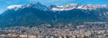 Renkli binalar, tarihi mimari ve açık mavi gökyüzünün altındaki kar kaplı Nordkette dağ sırasının yer aldığı Innsbruck, Avusturya 'nın havadan görünüşü.