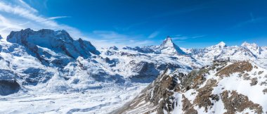 İsviçre Alpleri 'ni kaplayan kar manzarası Matterhorn zirvesi ve İsviçre' nin Zermatt kentindeki açık mavi gökyüzünün altındaki kayalık bir tepede bir gözlemevi ile kaplıydı..