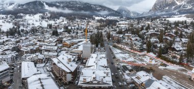 İtalya 'daki Cortina ve Ampezzo' nun havadan görünüşü, karla kaplı çatılar, alp mimarisi, bir inşaat sahası ve dramatik dağ zirvelerini gösteriyor..
