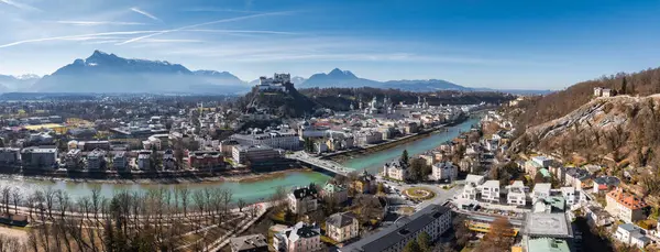 Salzburg, Avusturya 'nın havadan görünüşü, Hohensalzburg Kalesi, Salzach Nehri, eski barok kasaba, modern alanlar ve açık bir gökyüzü altındaki Alpler.