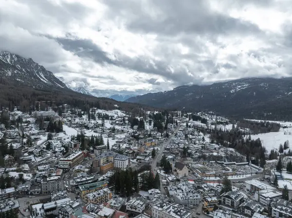 İtalya 'nın Cortina dAmpezzo kentinin havadan görünüşü, kar tozlu çatılar, orman tepeleri, dağ zirveleri ve 2026 Kış Olimpiyatları için yapılan inşaatı gösteriyor..