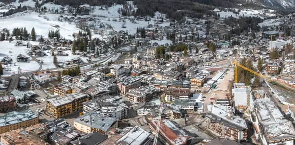 İtalya 'nın Dolomitlerdeki Cortina dAmpezzo kentinin havadan görünüşü, dağlarla kaplı dağları, dağlık binaları ve 2026 Kış Olimpiyatları için yapılan inşaatı gösteriyor..