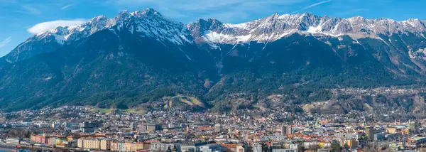 Renkli binalar, tarihi mimari ve açık mavi gökyüzünün altındaki kar kaplı Nordkette dağ sırasının yer aldığı Innsbruck, Avusturya 'nın havadan görünüşü.