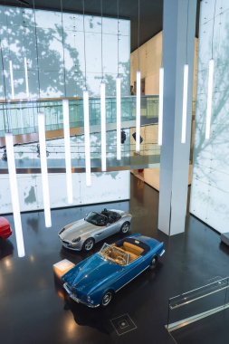 Münih 'teki BMW Müzesi' nin modern iç mekanı. Üstü açılabilir gümüş rengi, mavi, eski model, parlak ışıklandırma, cam balkon ve cilalı döşeme..