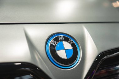 Münih 'teki BMW Müzesi' nde ışığı yansıtan gümüş renkli bir arabanın kaputunda mavi ve beyaz çeyrekli ikonik BMW logosu sergileniyor..